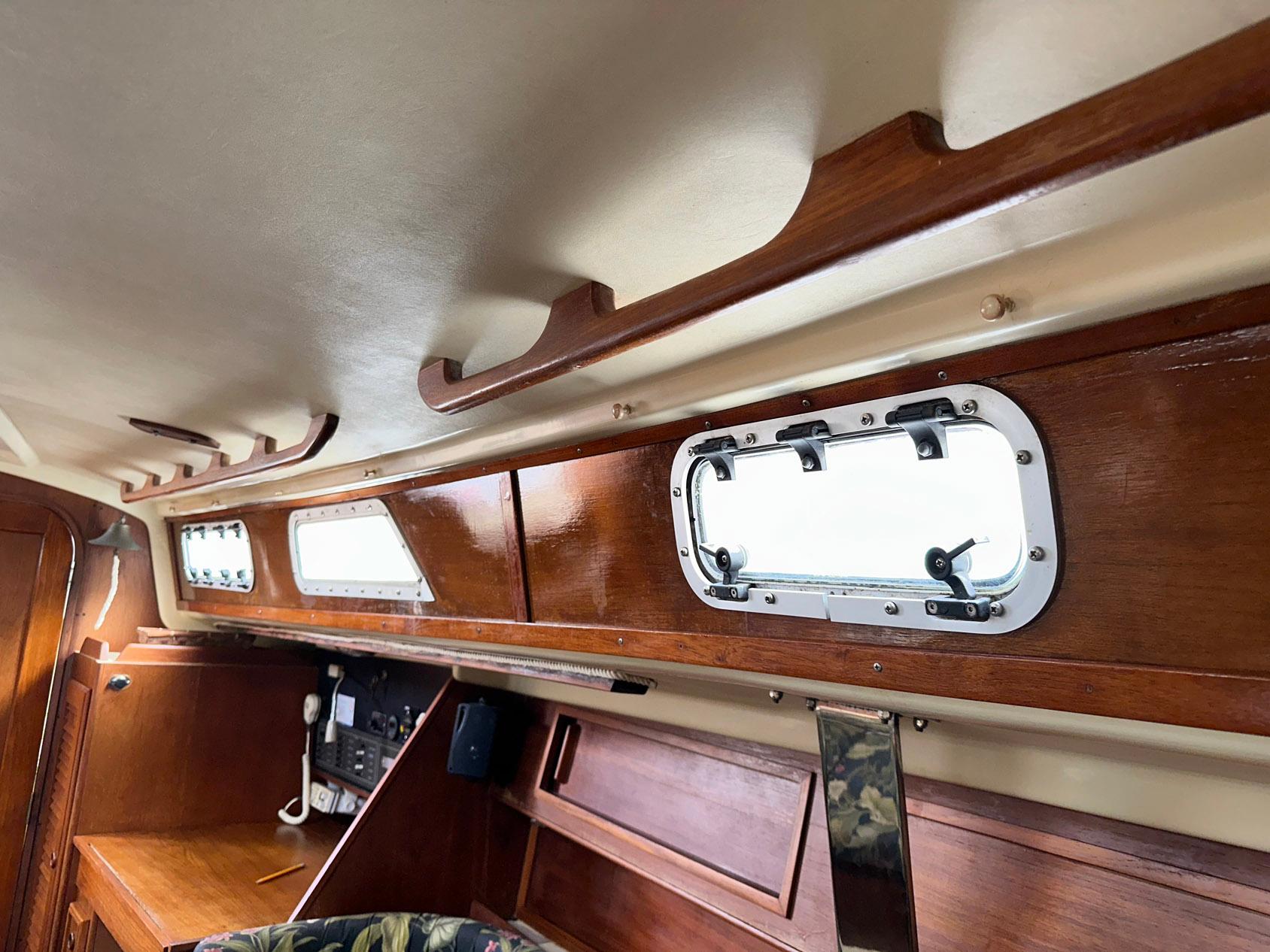 Interior of a 1987 Pearson 36-2 sailboat, featuring wooden cabinetry and portholes.