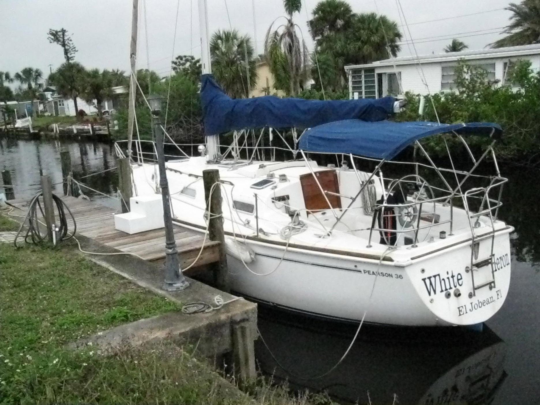 1987 Pearson 36-2 sailboat docked by a canal with blue canopy.