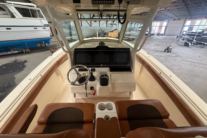  Yacht Photos Pics 2016 Scout 350 LXF boat interior with helm, steering wheel, and seating in a storage facility.