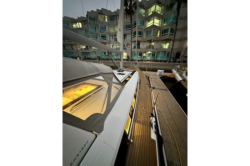 Champagne Yacht Photos Pics Beneteau Oceanis 55.1 yacht docked near modern apartments, evening lighting, 2021 model.