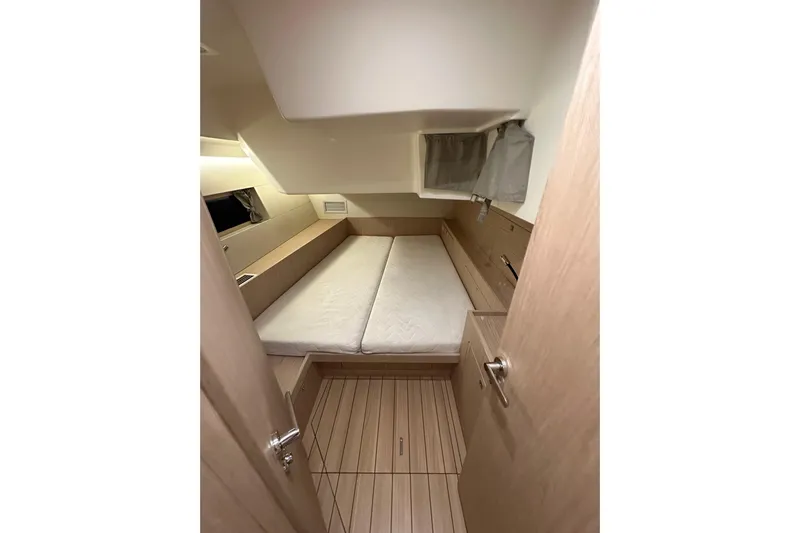 Champagne Yacht Photos Pics Interior cabin of 2021 Beneteau Oceanis 55.1 yacht, featuring a cozy bed and wooden flooring.