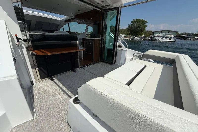  Yacht Photos Pics 2022 Cruisers Yachts 50 Cantius luxury deck with seating and table, docked at marina.