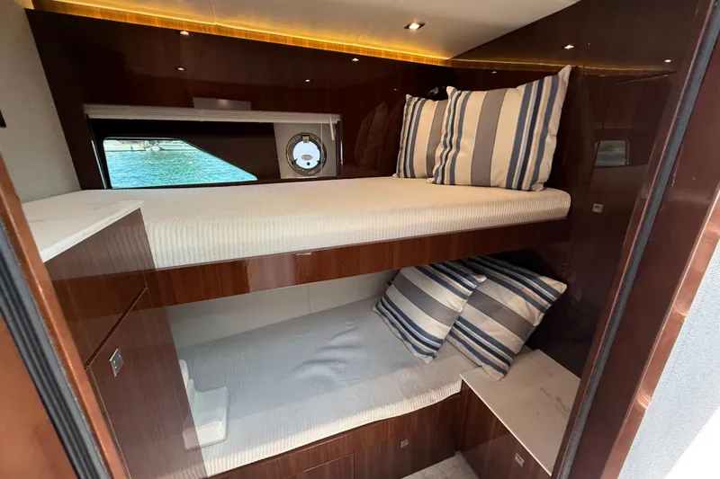  Yacht Photos Pics 2022 Cruisers Yachts 50 Cantius cabin with bunk beds and striped pillows.