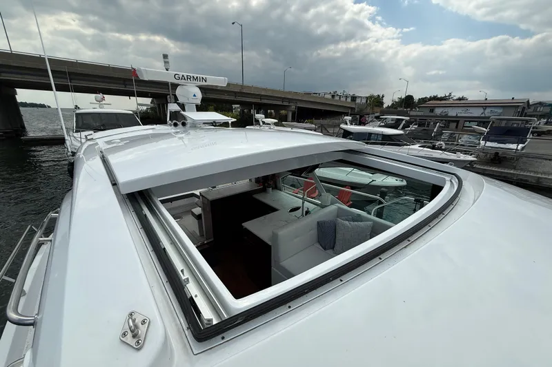  Yacht Photos Pics 2022 Cruisers Yachts 50 Cantius with open sunroof, docked near a bridge under cloudy skies.