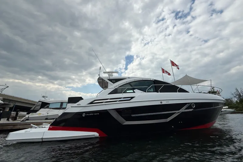  Yacht Photos Pics 2022 Cruisers Yachts 50 Cantius docked under cloudy sky, featuring sleek design and flags.
