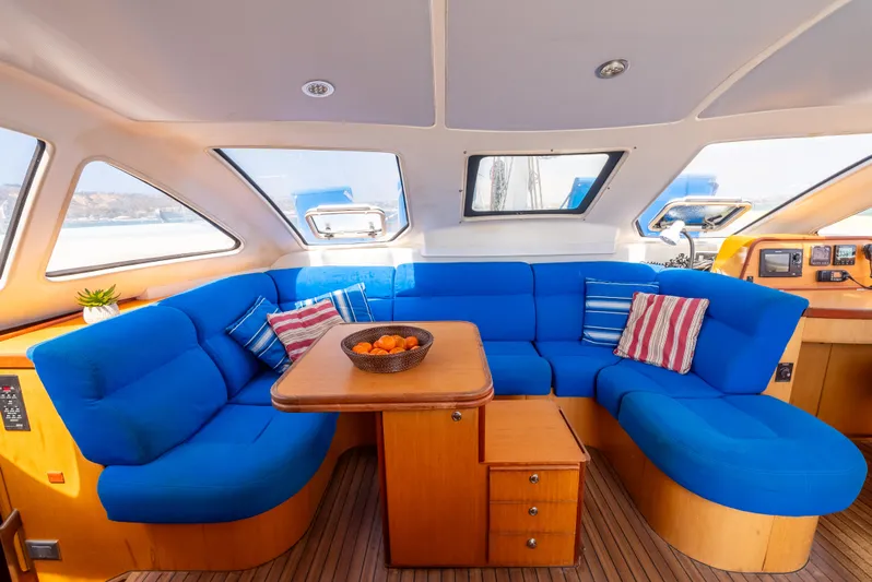 Nina May Yacht Photos Pics Catana 431 yacht interior, 2001 model, featuring blue seating and wooden table.