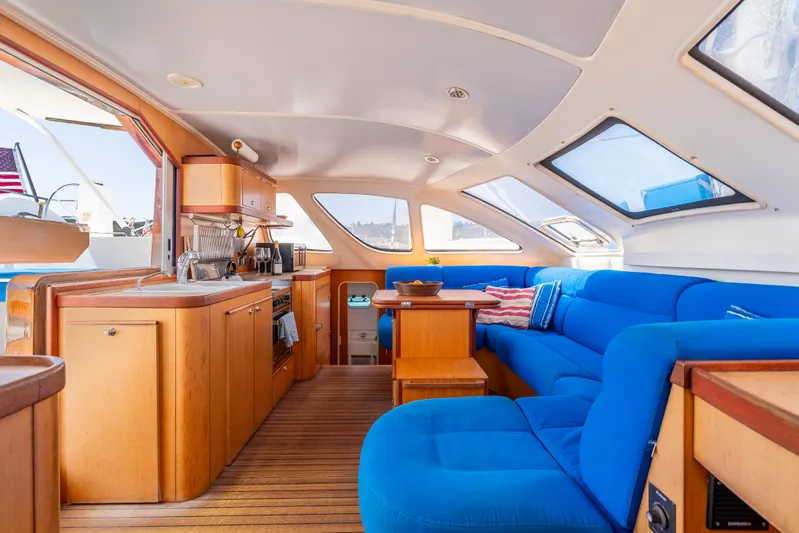 Nina May Yacht Photos Pics Interior of 2001 Catana 431 yacht with blue seating and wooden cabinetry.