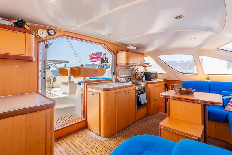 Nina May Yacht Photos Pics Spacious interior of 2001 Catana 431 yacht with wooden cabinetry and blue seating.