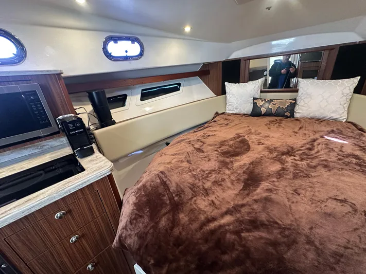  Yacht Photos Pics 2017 Pursuit OS 355 Offshore cabin with cozy bed, microwave, and wood cabinetry.