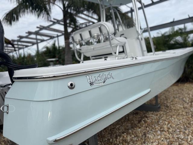 2025 BlackJack 224 boat, sleek design, parked on gravel with palm trees in background.