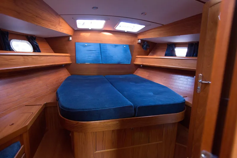 Tangent 2 Yacht Photos Pics Cozy cabin interior of 2002 Jeanneau Sun Odyssey 45.2 with blue cushions and wooden finish.