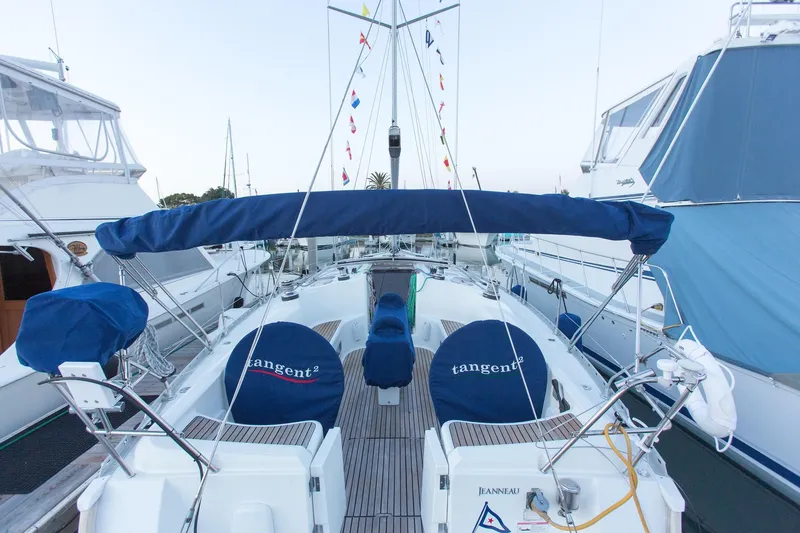 Tangent 2 Yacht Photos Pics Jeanneau Sun Odyssey 45.2 sailboat, 2002 model, docked with blue covers and nautical flags.