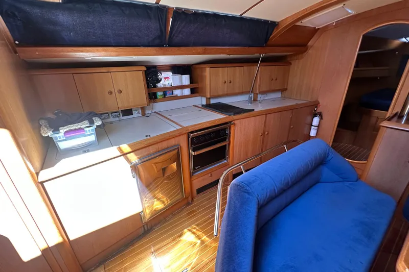 Tangent 2 Yacht Photos Pics Interior of 2002 Jeanneau Sun Odyssey 45.2 yacht with wooden cabinetry and blue seating.