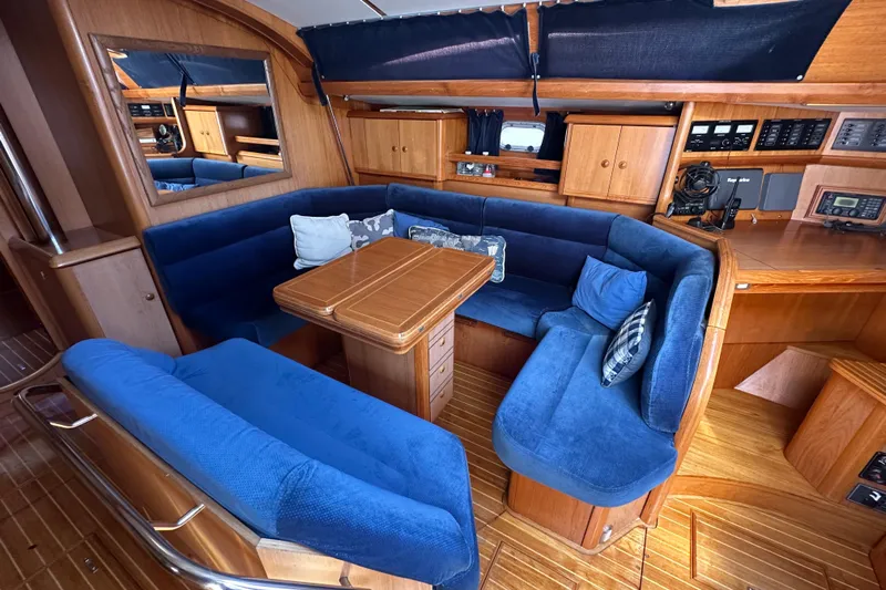 Tangent 2 Yacht Photos Pics Luxurious interior of 2002 Jeanneau Sun Odyssey 45.2 yacht with blue seating and wooden finishes.