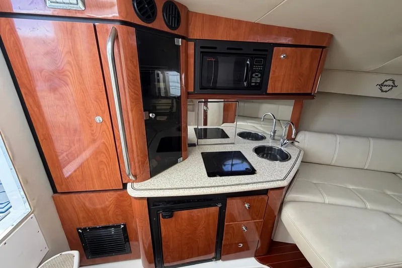  Yacht Photos Pics 2007 Fountain 38 Tournament Edition boat interior with kitchenette, featuring wood cabinetry and modern appliances.