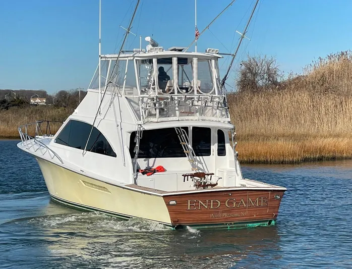 End Game Yacht Photos Pics 2001 Ocean Yachts 56 Super Sport cruising on a calm waterway, surrounded by reeds.