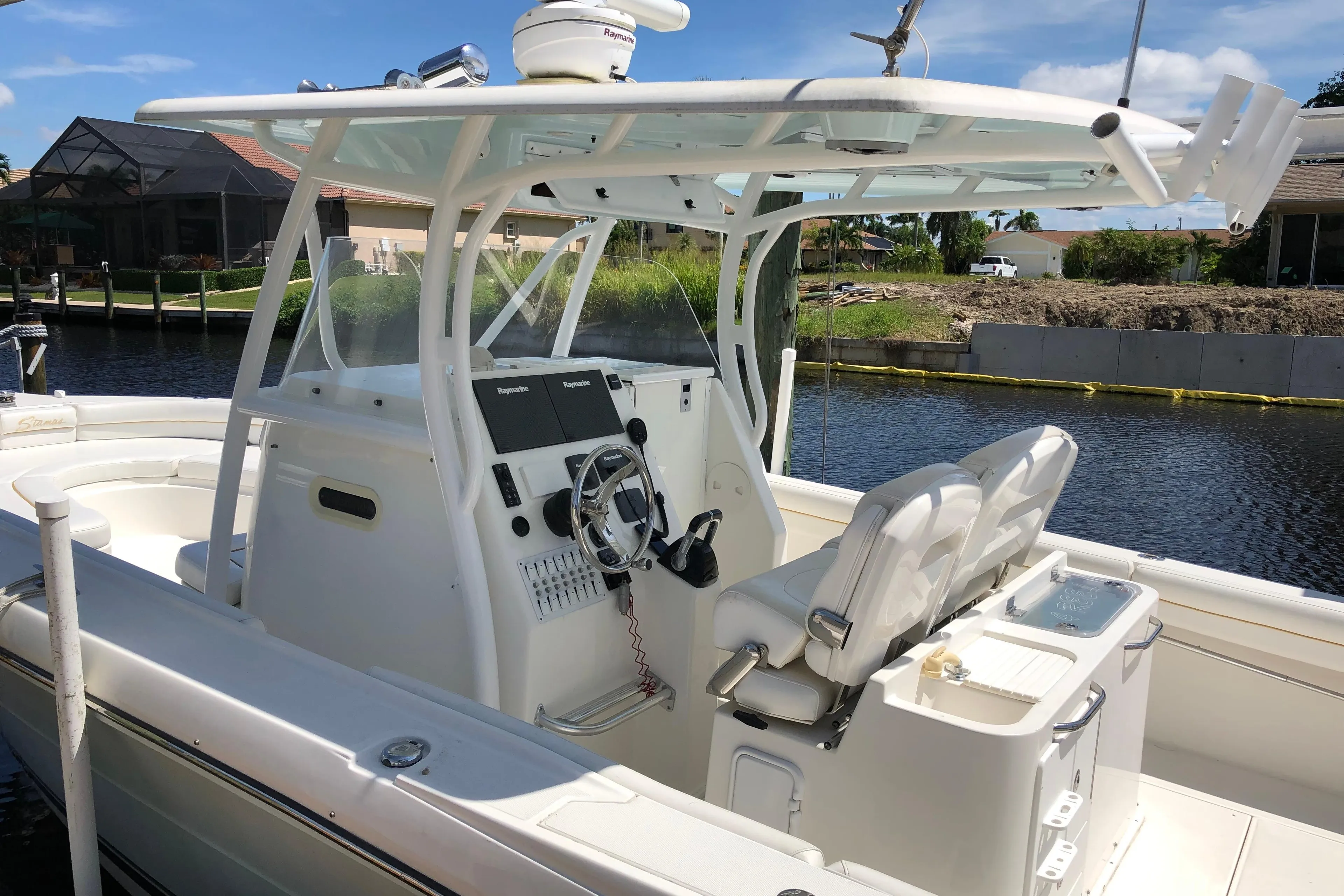 2016 Tarpon 326 boat with dual seats and navigation equipment, docked by a canal.