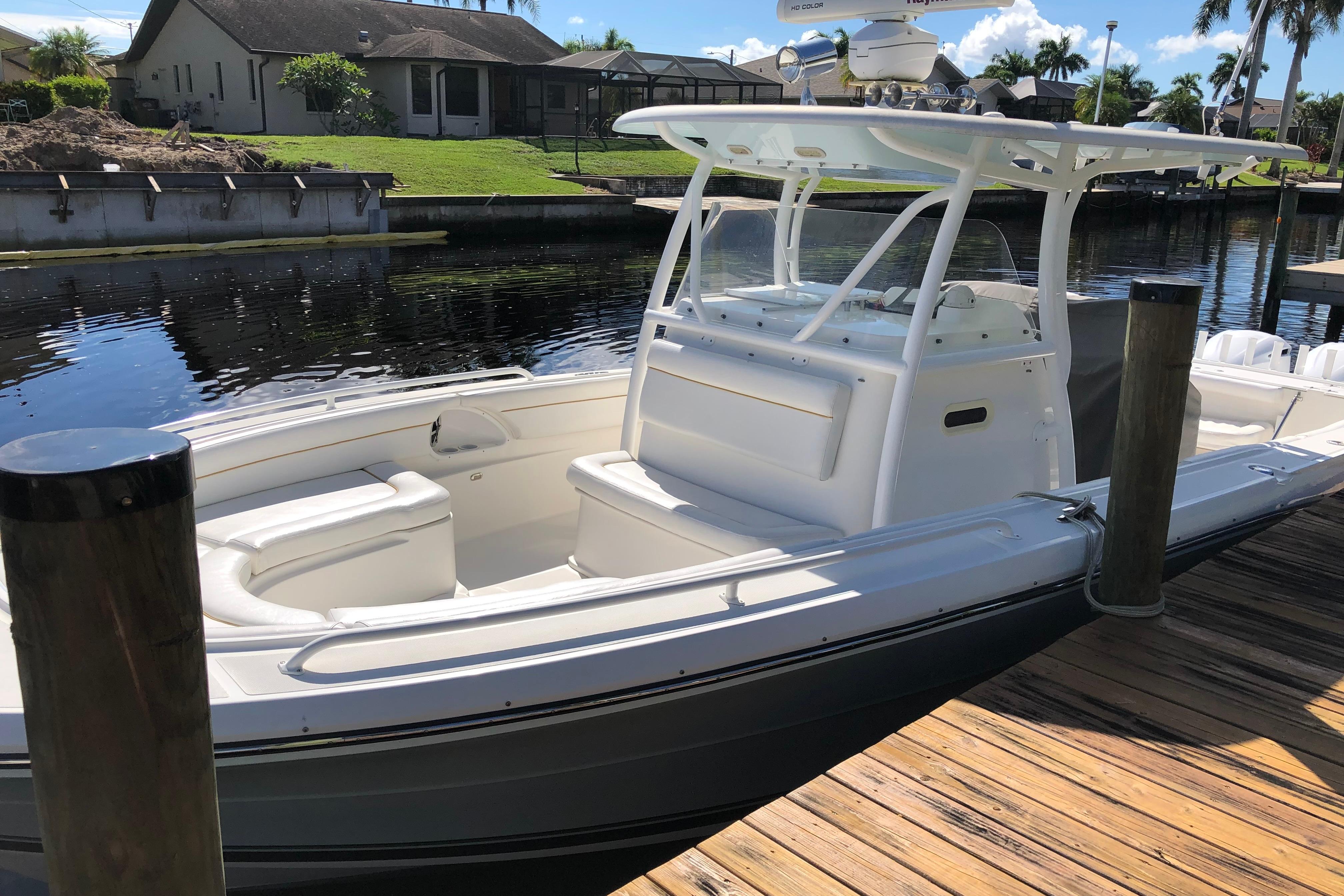 2016 Tarpon 326 boat docked by a wooden pier, under clear skies.