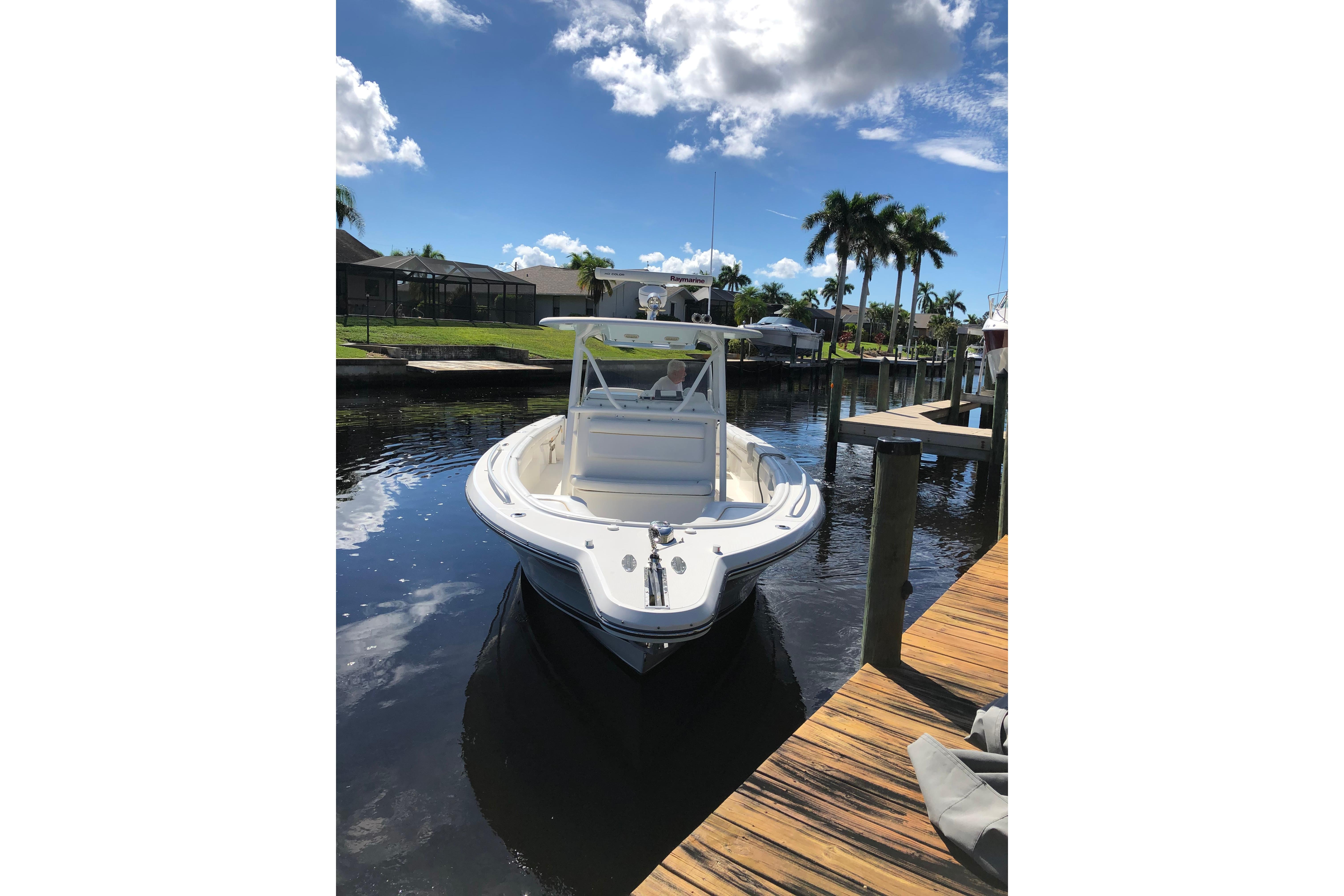 2016 Tarpon 326 boat docked on a sunny day with palm trees in the background.