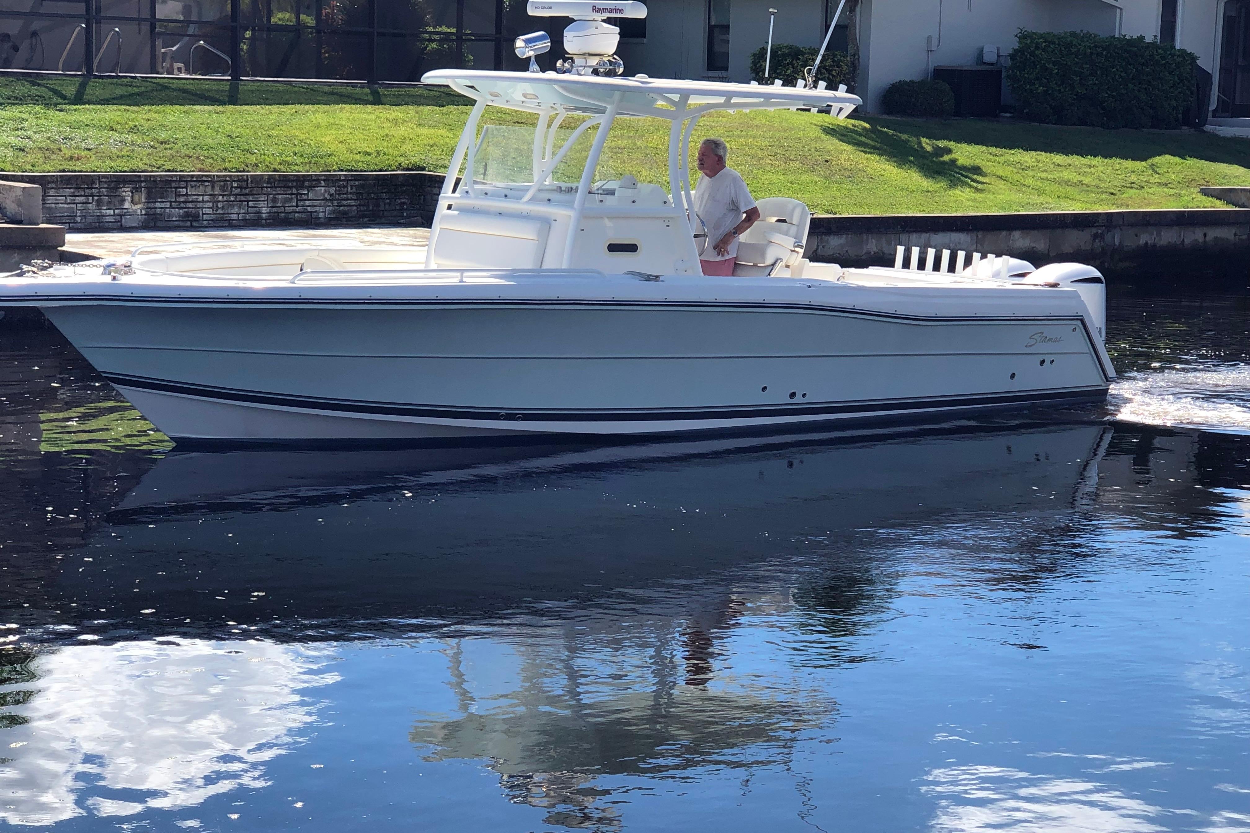 A 2016 Tarpon 326 boat cruising on calm water near a grassy shoreline.
