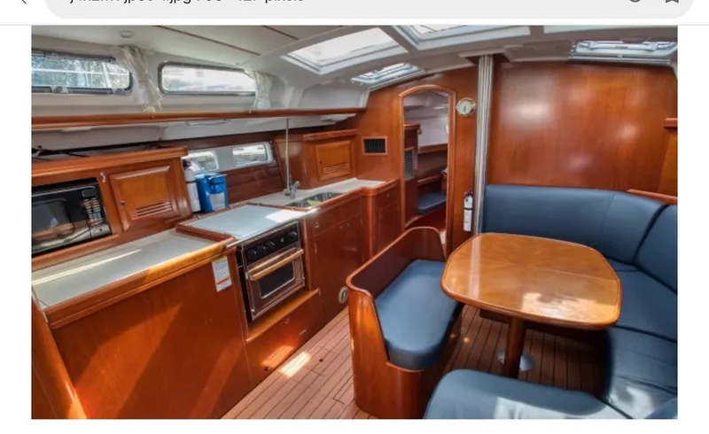 Vita Amoris Yacht Photos Pics Interior of 2005 Beneteau 423 yacht with wood finish, kitchen, and seating area.