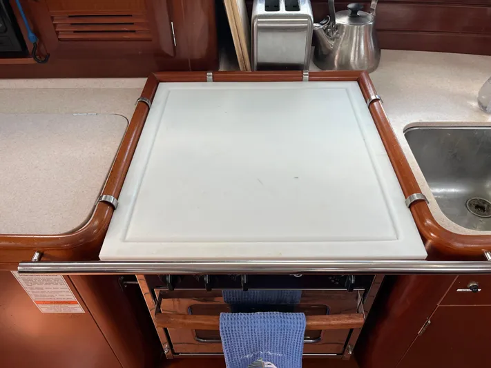 Vita Amoris Yacht Photos Pics Galley kitchen in 2005 Beneteau 423 sailboat with cutting board and sink.