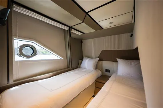  Yacht Photos Pics Luxurious twin cabin in 2023 Ferretti Yachts 720, featuring modern design and porthole window.
