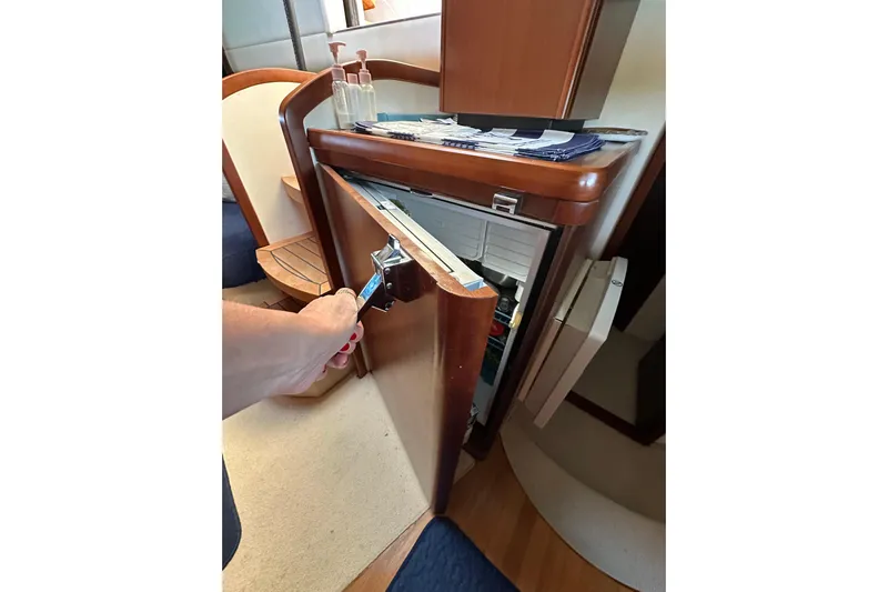 Yacht Photos Pics Interior of 2016 Princess V45 yacht showing an open wooden cabinet with a fridge.