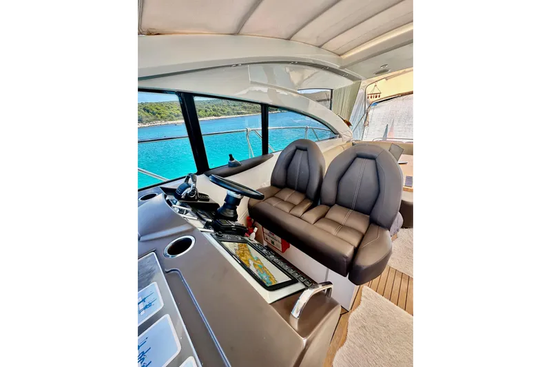  Yacht Photos Pics Interior of 2016 Princess V45 yacht with dual seats and steering, overlooking blue water.