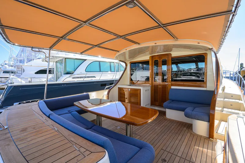 Nauti Dog Yacht Photos Pics 2023 Palm Beach Motor Yachts PB55 interior with elegant seating and wooden table.