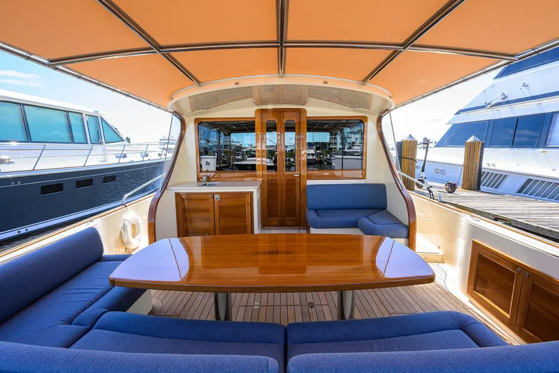 Nauti Dog Yacht Photos Pics 2023 Palm Beach Motor Yachts PB55 interior with elegant seating and wooden table.