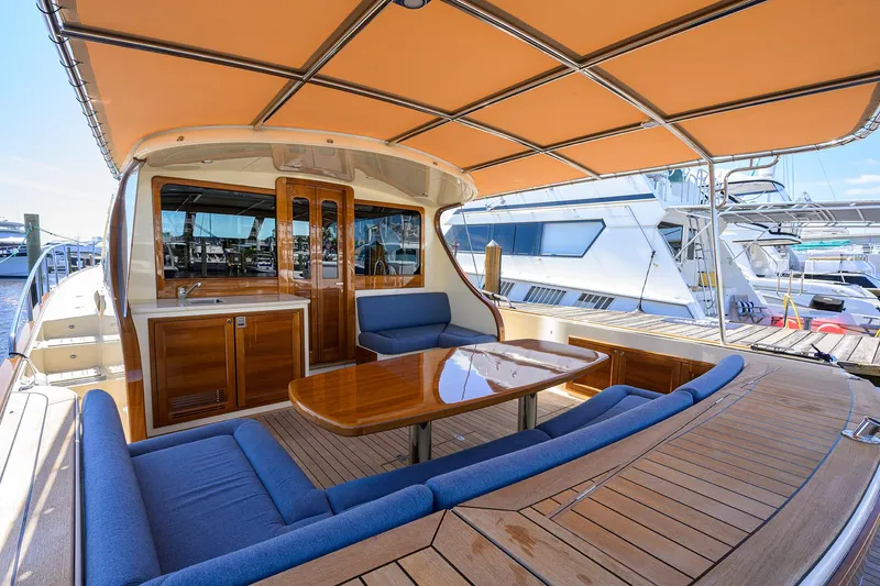 Nauti Dog Yacht Photos Pics 2023 Palm Beach Motor Yachts PB55 with spacious deck, elegant seating, and wooden finishes.