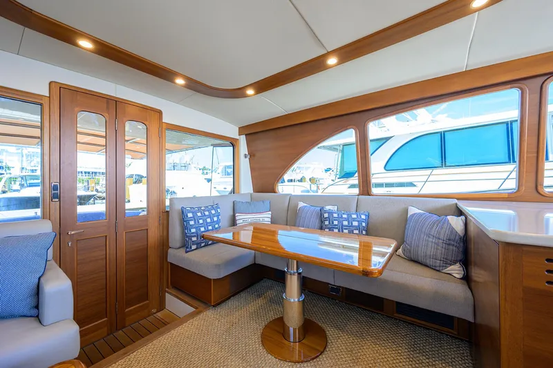 Nauti Dog Yacht Photos Pics Luxurious interior of 2023 Palm Beach Motor Yachts PB55 with elegant seating and wooden finishes.
