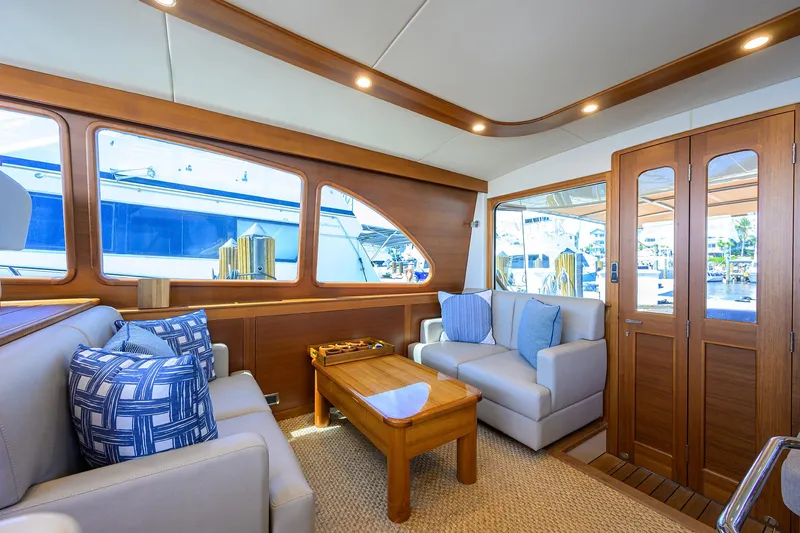 Nauti Dog Yacht Photos Pics Luxurious interior of 2023 Palm Beach Motor Yachts PB55 with elegant wood finishes and plush seating.