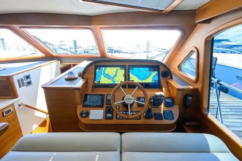 Nauti Dog Yacht Photos Pics Helm of 2023 Palm Beach Motor Yachts PB55 with navigation screens and wooden steering wheel.
