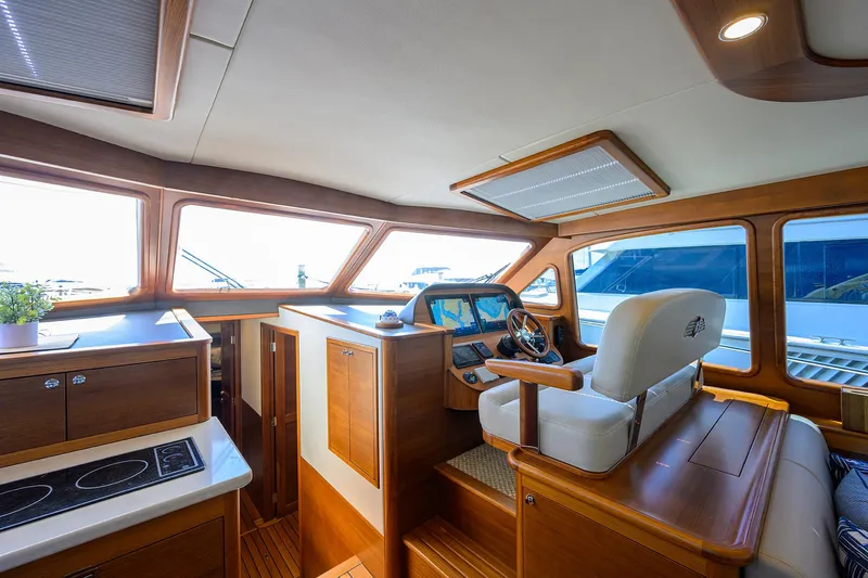 Nauti Dog Yacht Photos Pics 2023 Palm Beach Motor Yachts PB55 interior with helm, luxurious seating, and modern kitchen area.