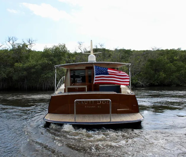 Nauti Dog Yacht Photos Pics 2023 Palm Beach Motor Yachts PB55 cruising with American flag on waterway.