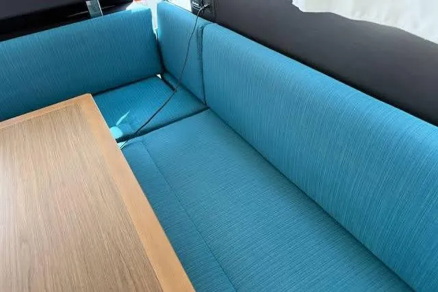 Sweet & Salty Yacht Photos Pics Interior seating area of a 2019 Jeanneau Velasco 37F with blue upholstery and wooden table.