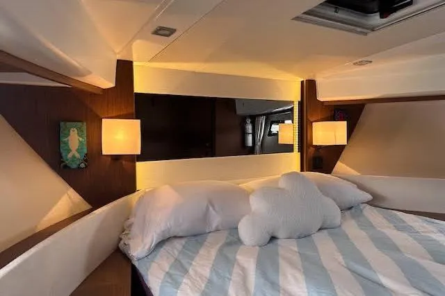 Sweet & Salty Yacht Photos Pics Cozy bedroom interior of 2019 Jeanneau Velasco 37F yacht with striped bedding and soft lighting.