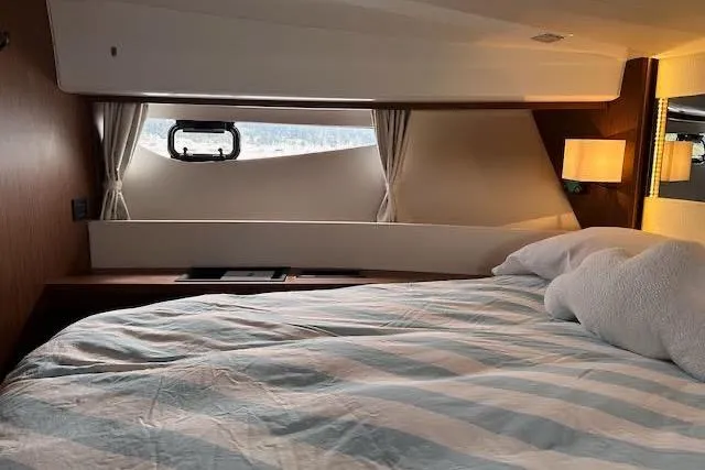 Sweet & Salty Yacht Photos Pics Cozy cabin interior of 2019 Jeanneau Velasco 37F with striped bedding and window view.