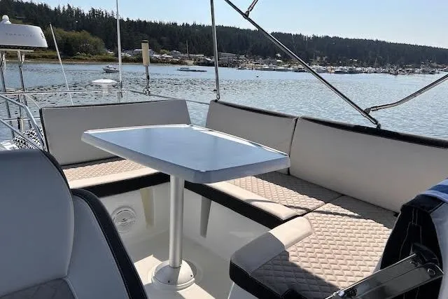 Sweet & Salty Yacht Photos Pics 2019 Jeanneau Velasco 37F yacht with outdoor seating and table, docked by a scenic waterfront.