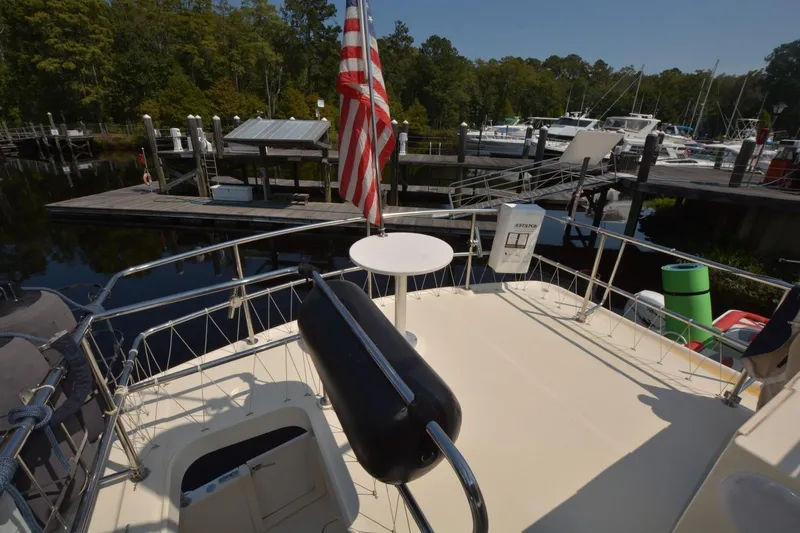 Standing By Yacht Photos Pics 2004 Mainship 400 Trawler deck with American flag, docked at marina.