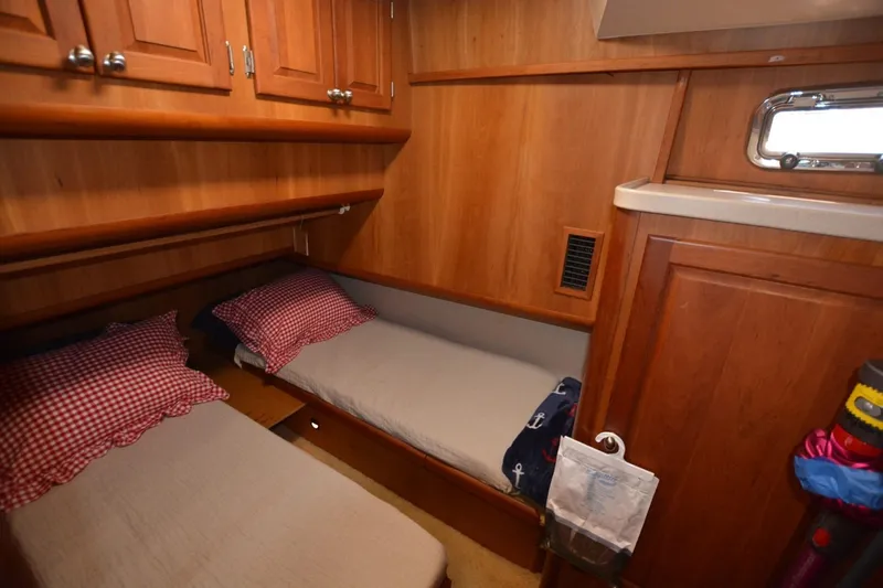 Standing By Yacht Photos Pics 2004 Mainship 400 Trawler cabin with twin beds, wooden cabinetry, and a small window.