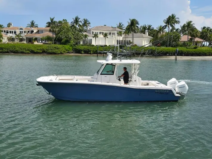  Yacht Photos Pics 2023 Caymas 30 CT boat cruising on a scenic waterway near luxury homes.