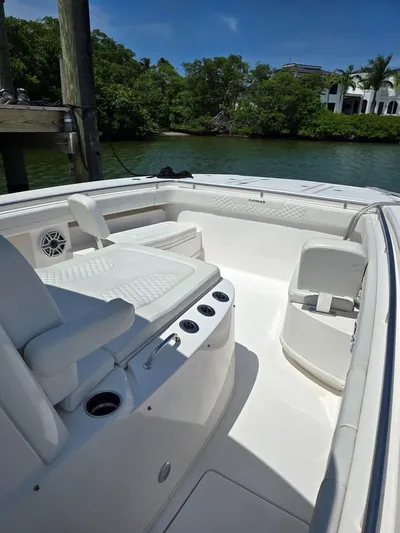  Yacht Photos Pics 2023 Caymas 30 CT boat interior with white seating and cup holders, docked by lush greenery.