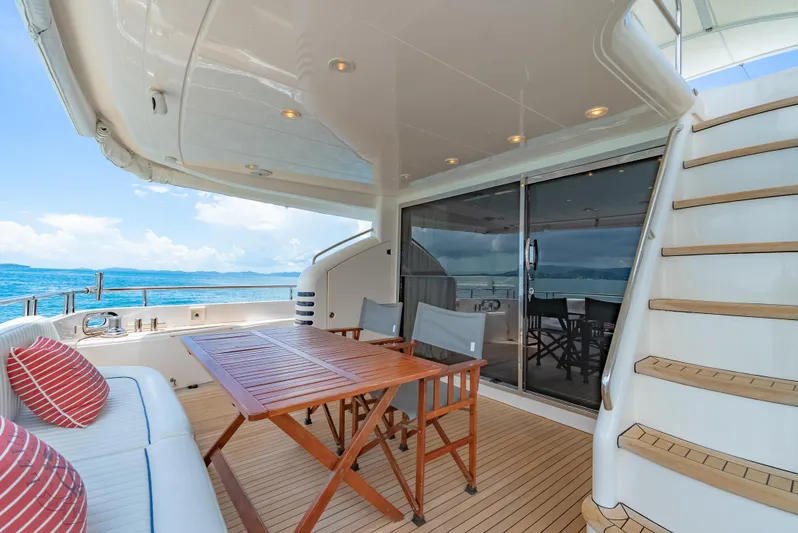 Blue Rose Yacht Photos Pics Luxury yacht deck with seating, wooden table, and ocean view; Princess 23M, 2006 model.