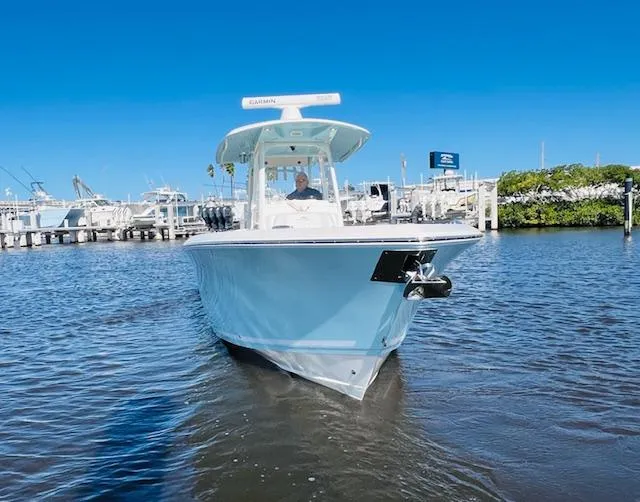  Yacht Photos Pics 2021 Cobia 301 Center Console boat on water near marina under clear blue sky.