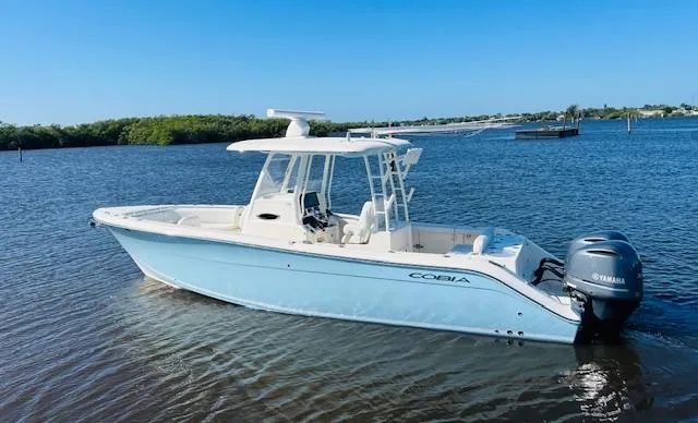  Yacht Photos Pics 2021 Cobia 301 Center Console boat on calm water, featuring a sleek design and Yamaha engine.