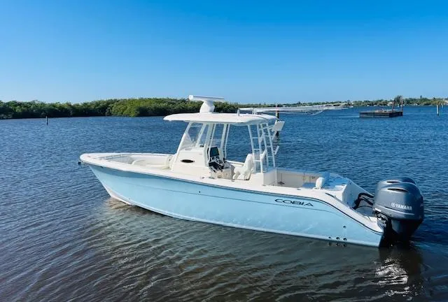  Yacht Photos Pics 2021 Cobia 301 Center Console boat on calm water, featuring a sleek design and Yamaha engine.