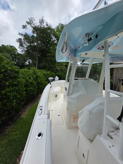  Yacht Photos Pics 2021 Cobia 301 Center Console boat with covered seating, docked near lush greenery.